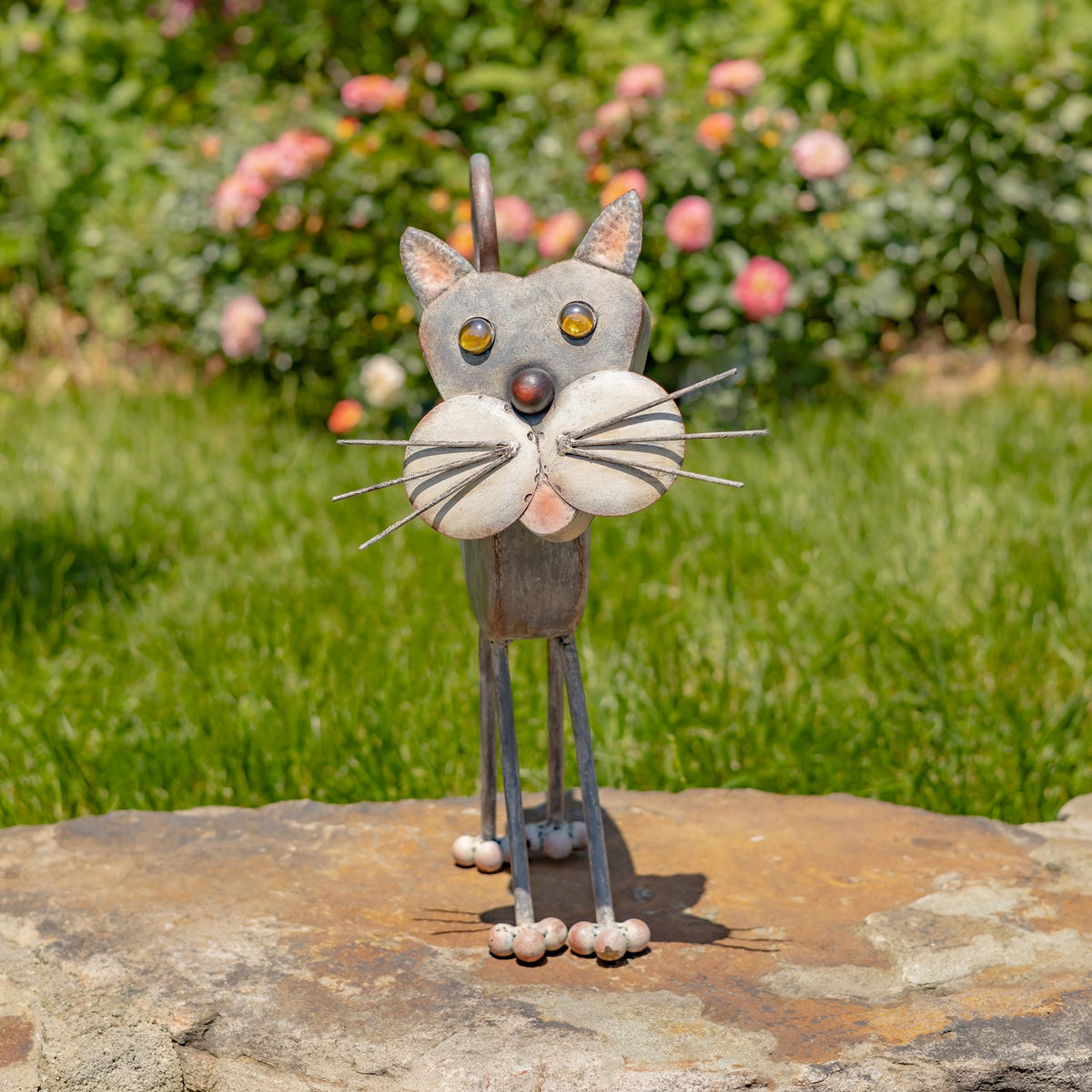 Front view of a freestanding iron cat planter outdoors on a stone slab