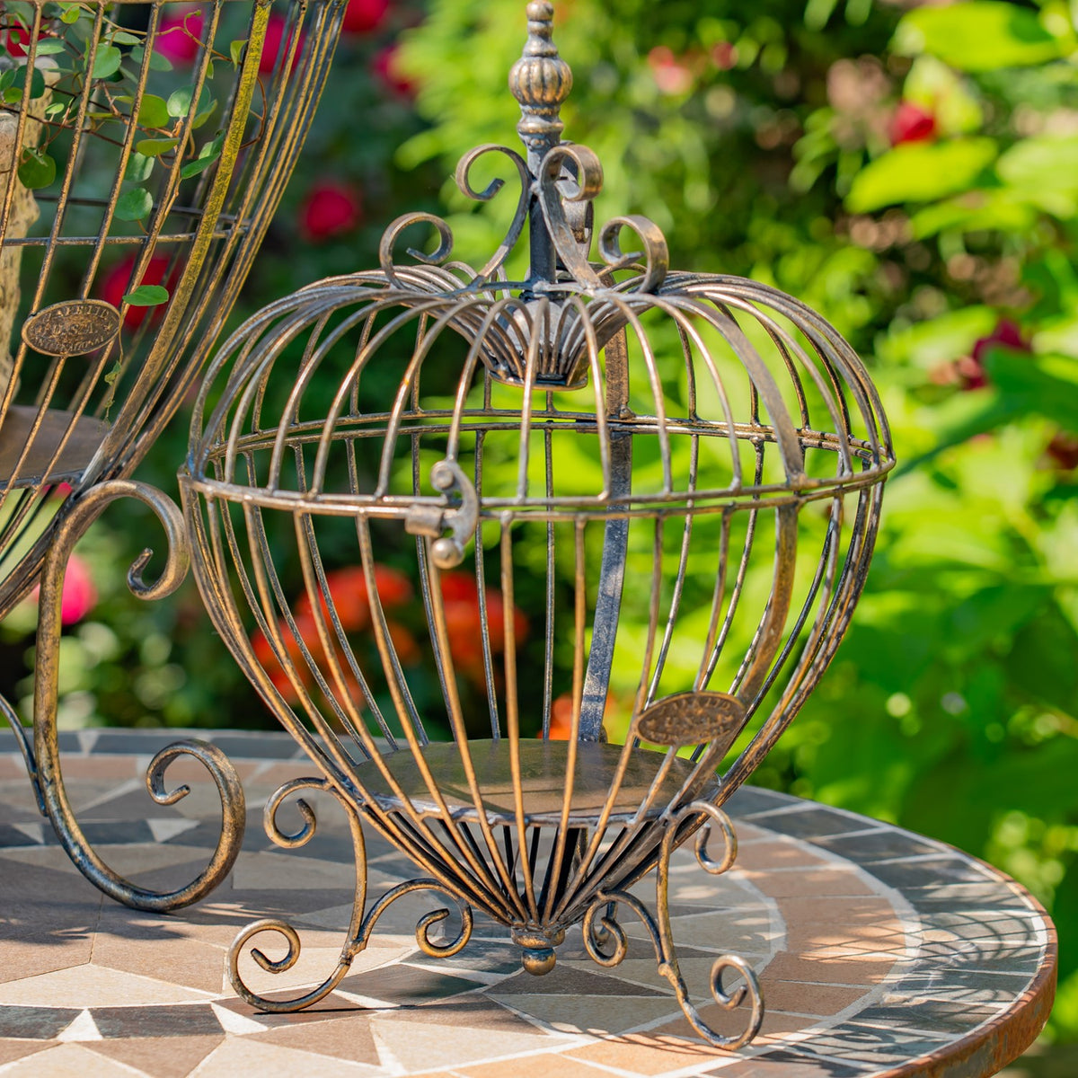 Smaller heart-shaped wire stand on a tiled table, with part of the larger matching stand visible beside it.