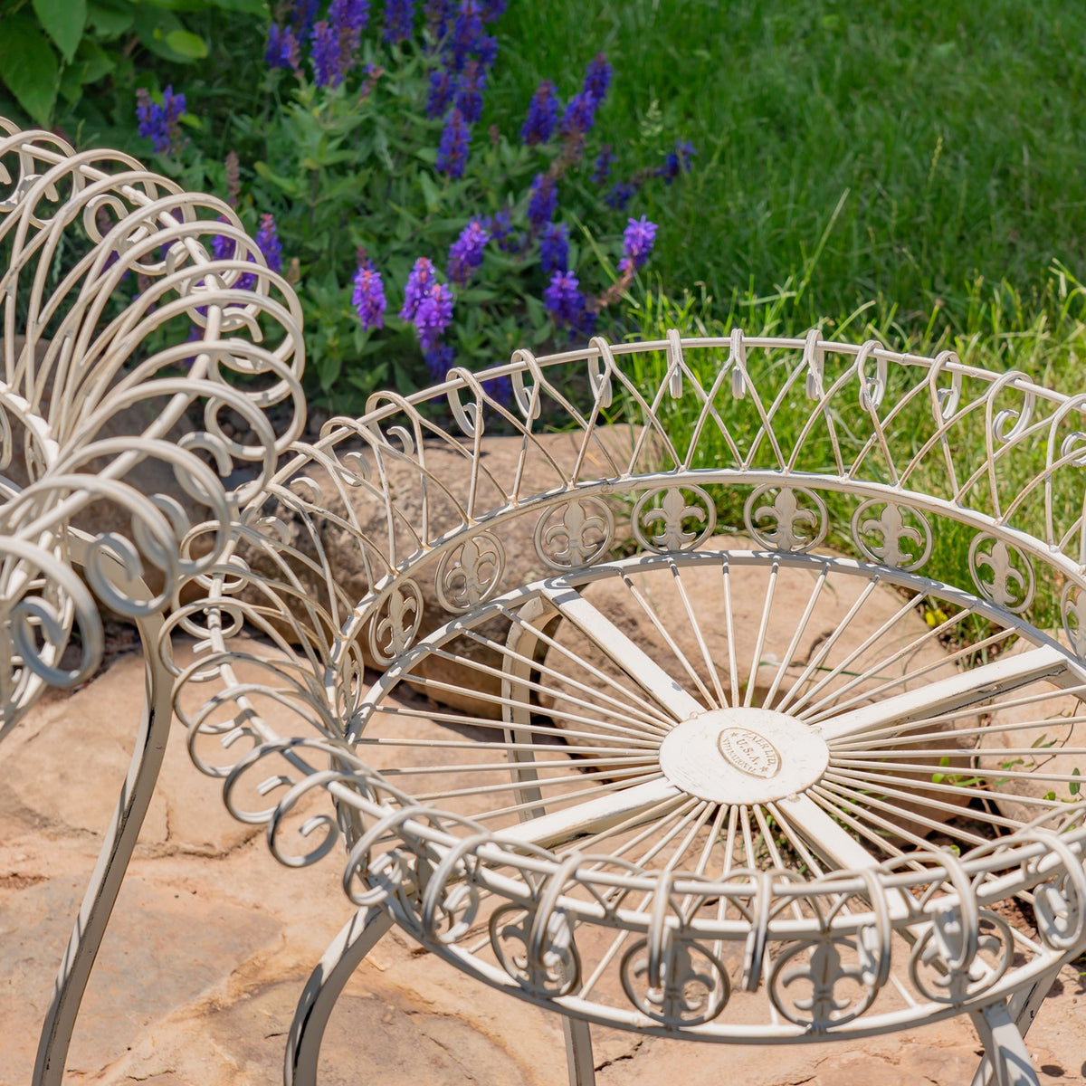 Close-up of a pale wire basket stand showing its curled rim, scrollwork, and radiating base wires.
