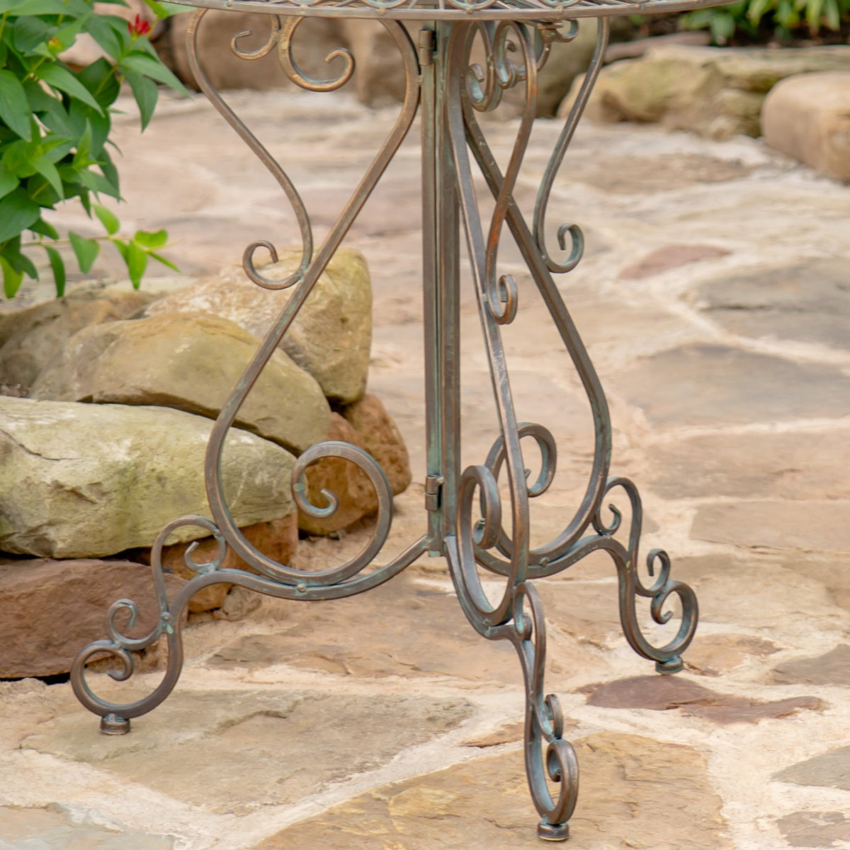 Close view of curled iron legs and scrollwork on a stone patio.