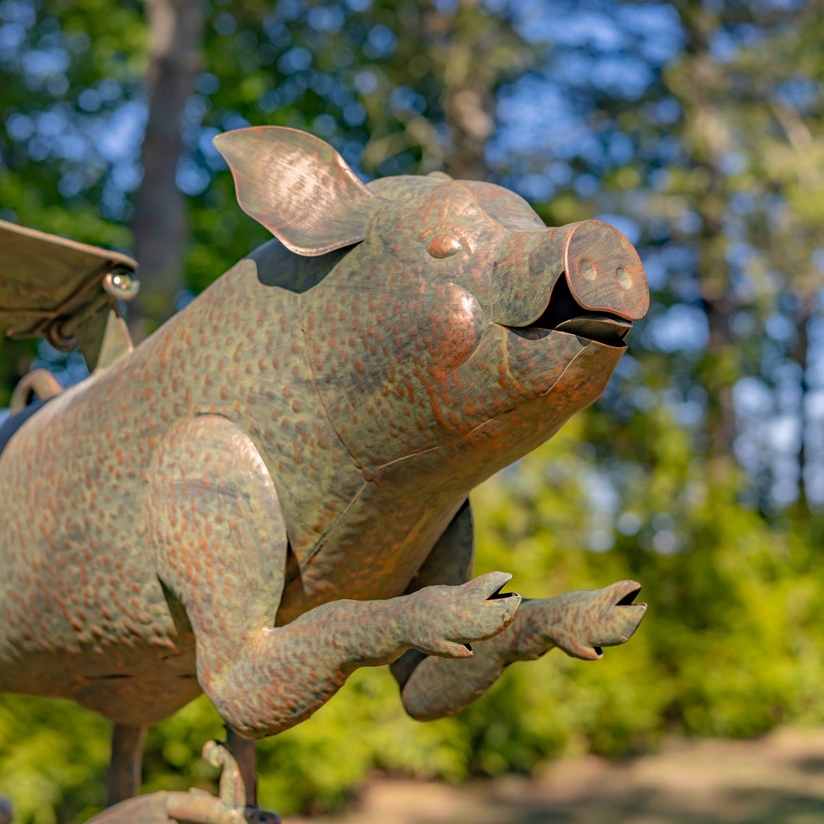 Close view of the pig’s textured metal body, wings, snout, and outstretched legs.