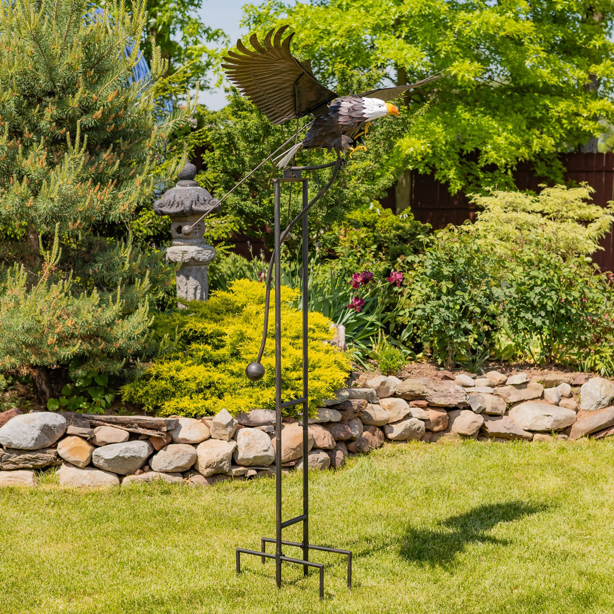 Full-height eagle garden stake standing among lawn and garden beds