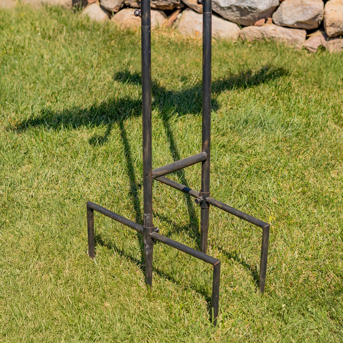 Close view of the metal stake’s rectangular stabilizing feet set into a lawn.