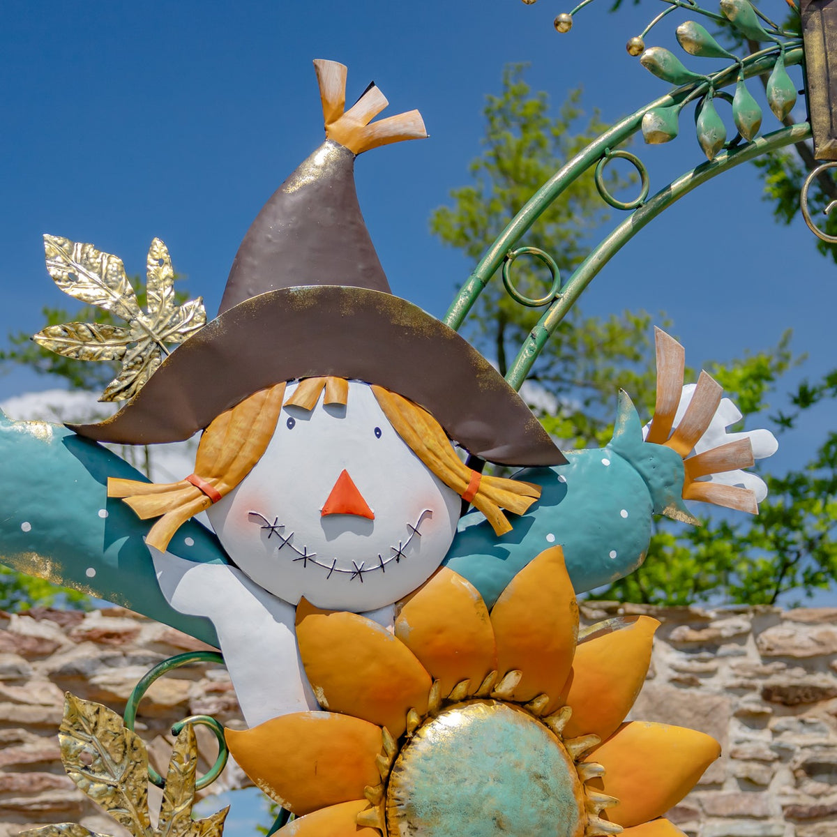 Close-up of a smiling scarecrow in a brown pointed hat, set above orange sunflower petals.