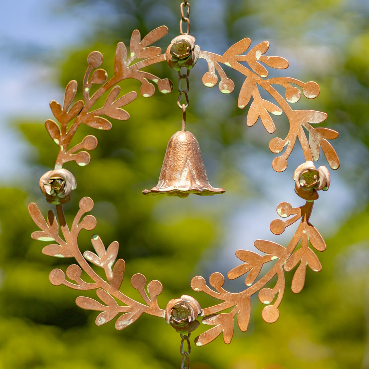 Close view of the leafy metal ring, small decorative bells, and a bell-shaped chime at its center.