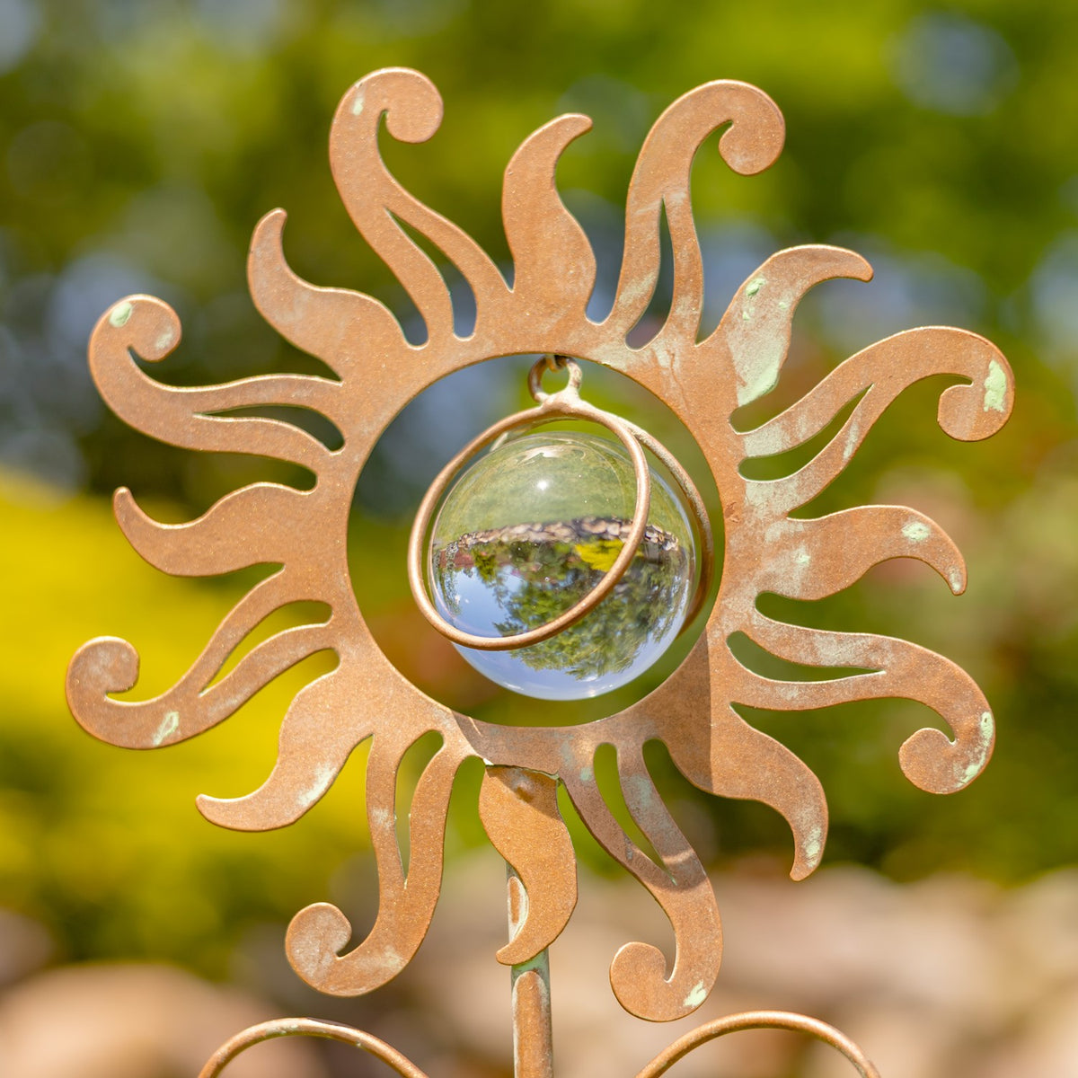 Close view of the curled copper sun surrounding a reflective glass sphere.
