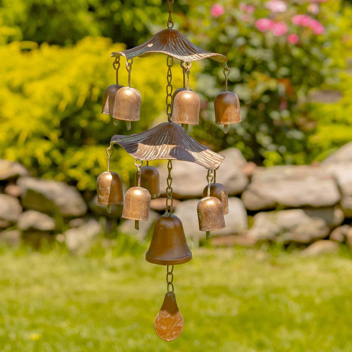 Tiered copper-toned bells hanging beneath the bird feeder