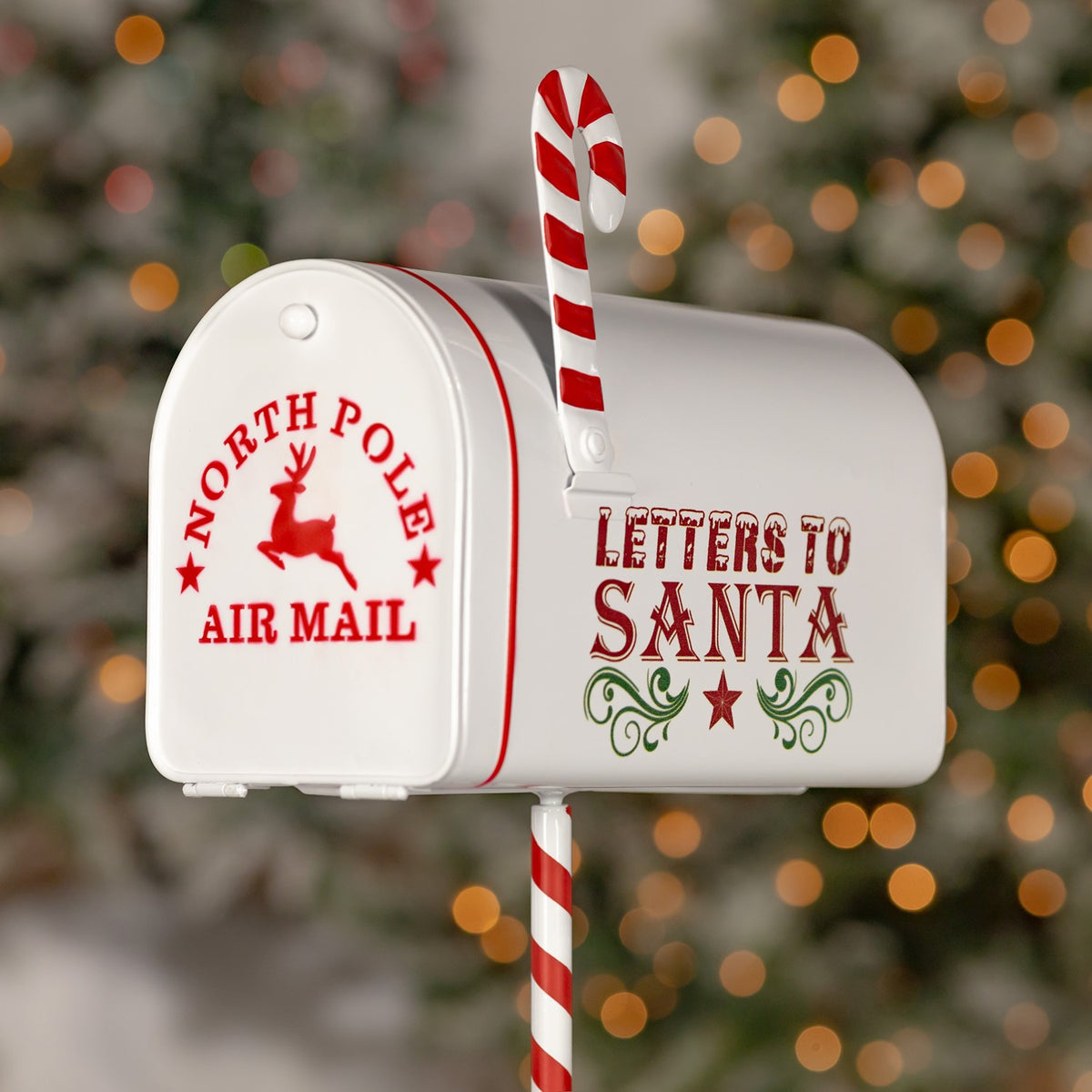 White mailbox with red lettering and a striped candy cane post against a blurred festive background.