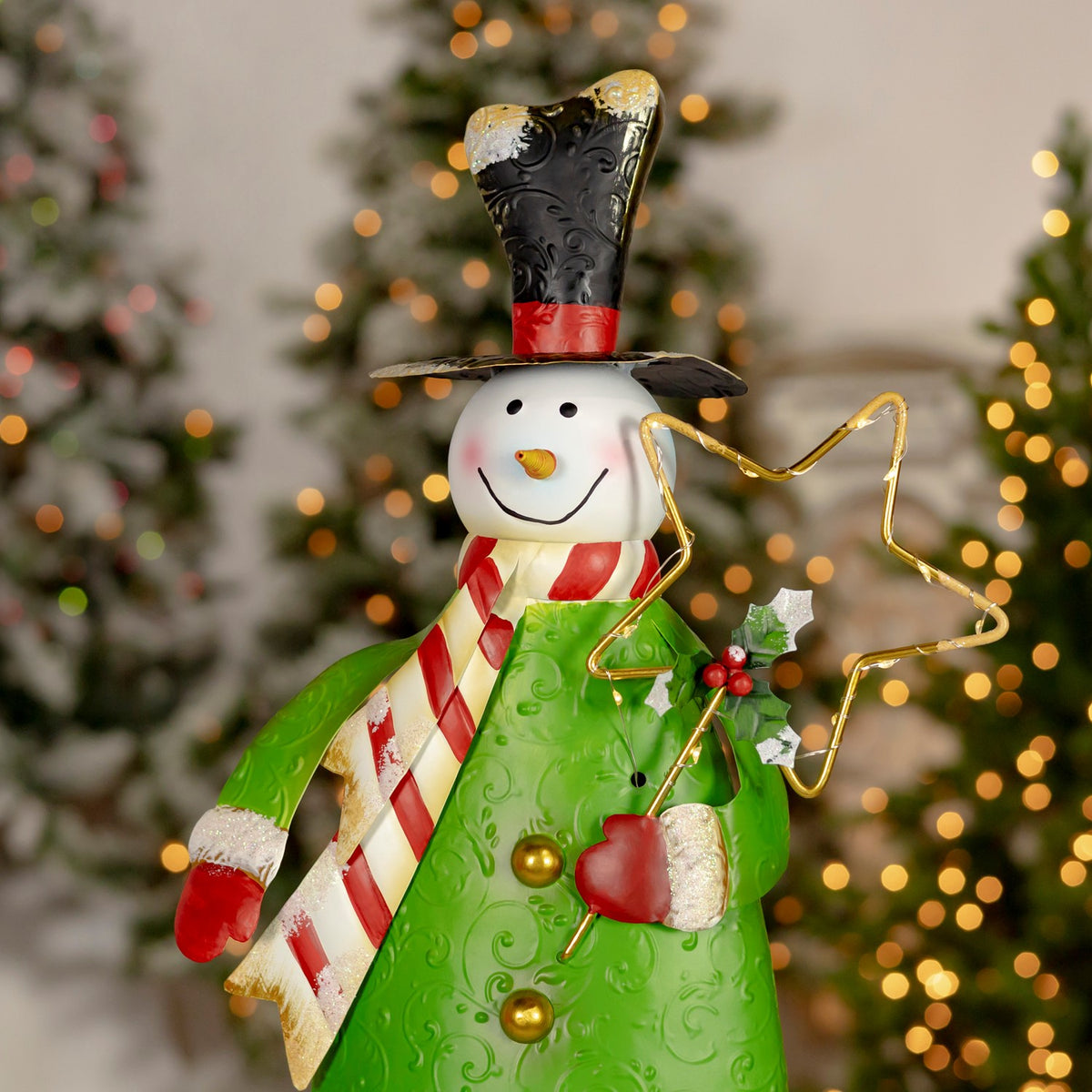 Green-coated snowman wearing a striped scarf and holding a large gold wire star.
