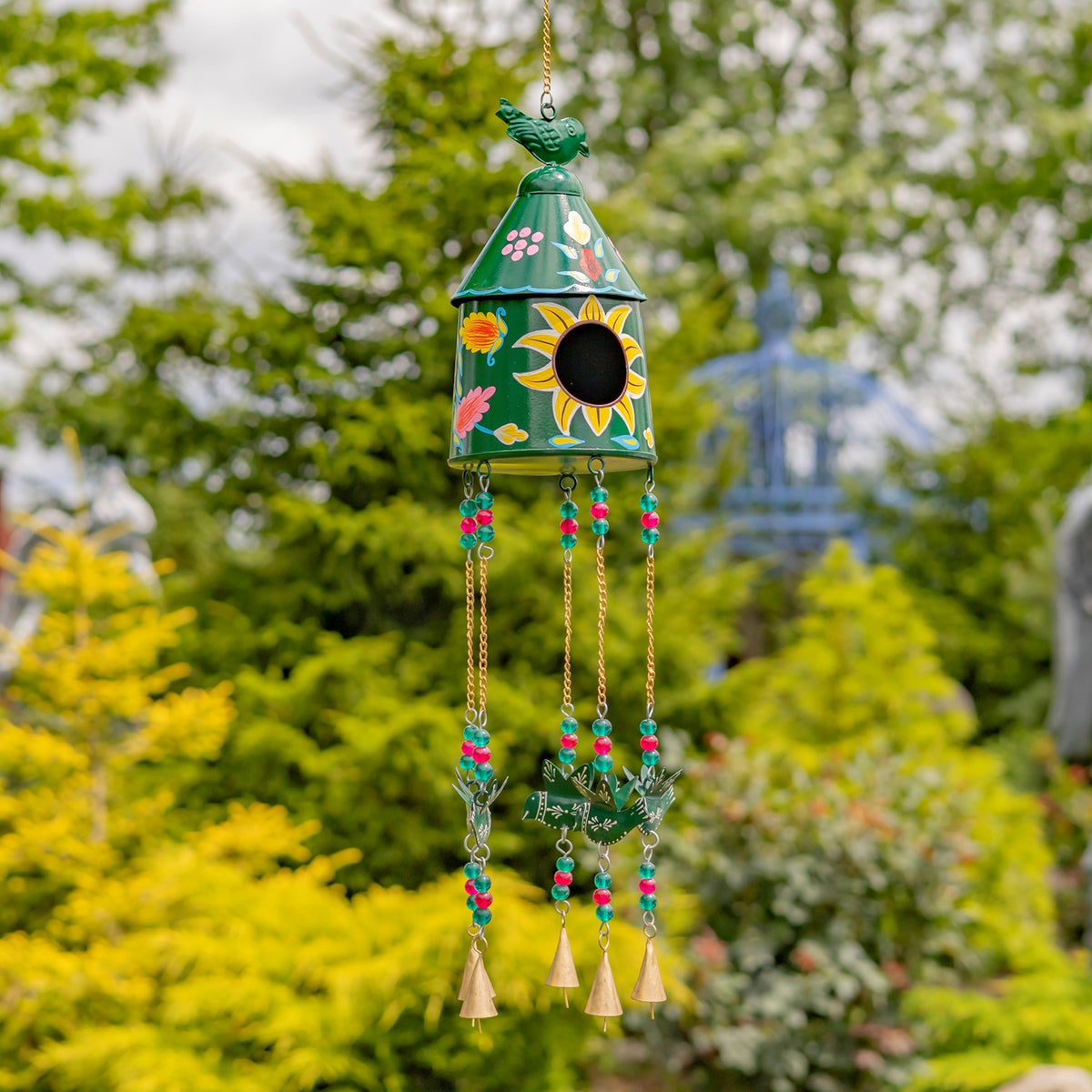 Green birdhouse wind chime decorated with flowers and a sun, with beaded strands and small bells.