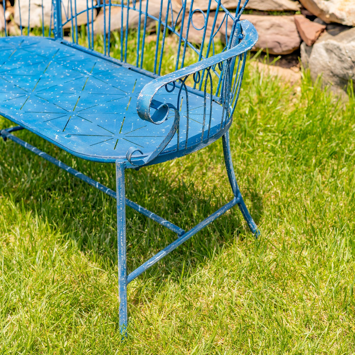 Close angled view of the blue iron bench seat, curled armrest, and legs