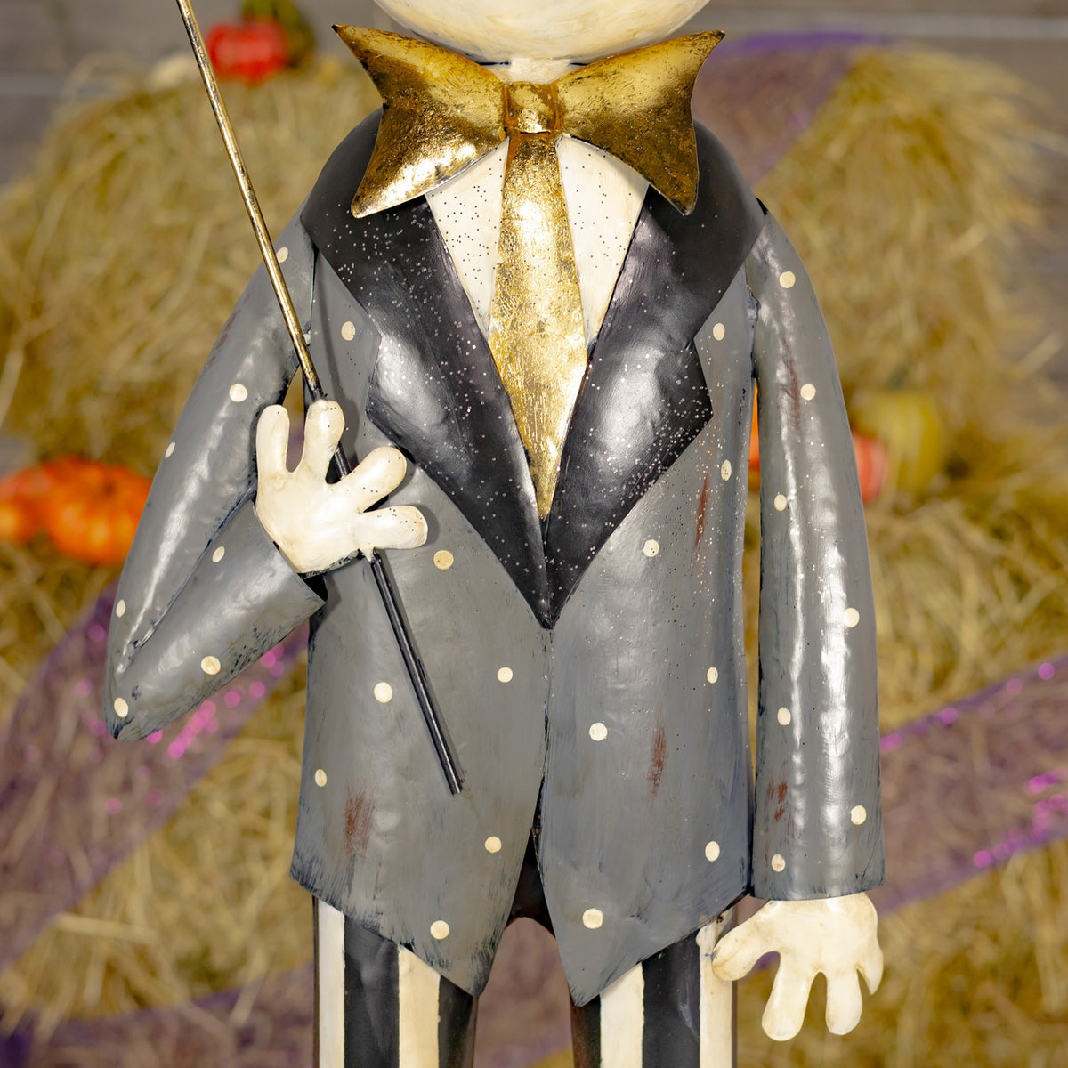 Close view of the skeleton's speckled gray suit, gold tie, and bony hand holding the umbrella shaft.