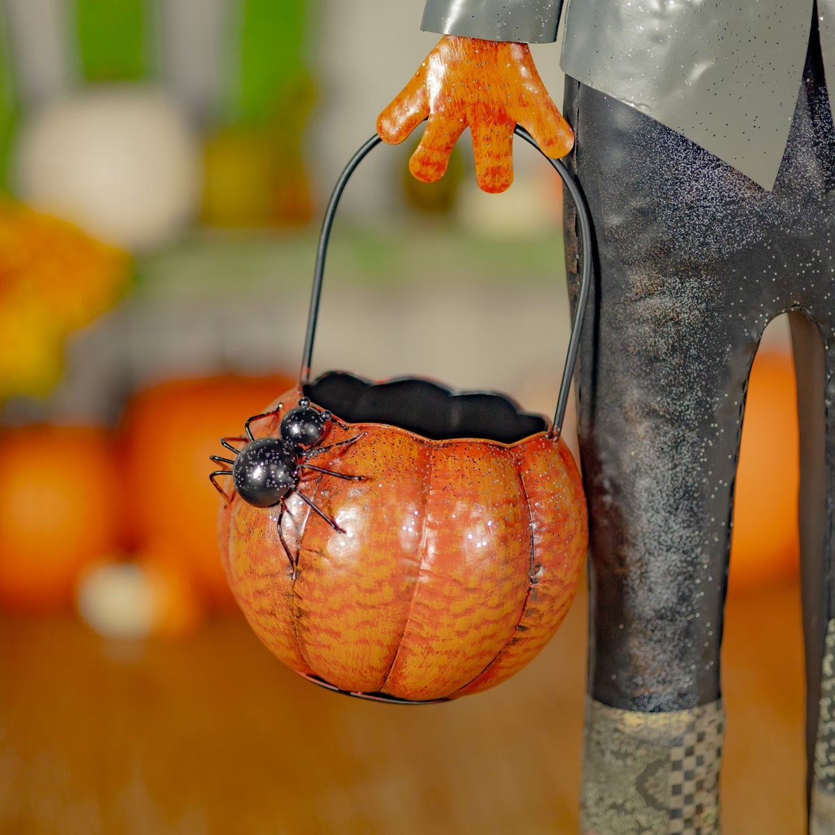 Close-up of the orange basket with black spiders hanging beside the figure