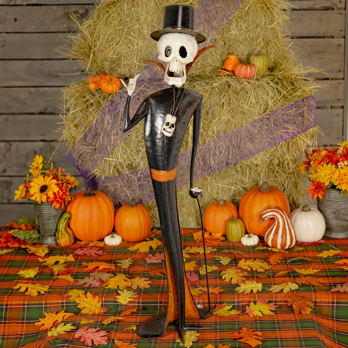 Single skeleton figurine in a black top hat posed among pumpkins