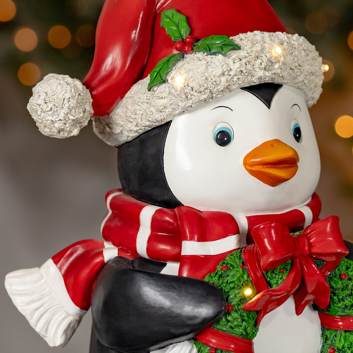 Side view showing the penguin's scarf, black flipper, white tail, and wreath lights.