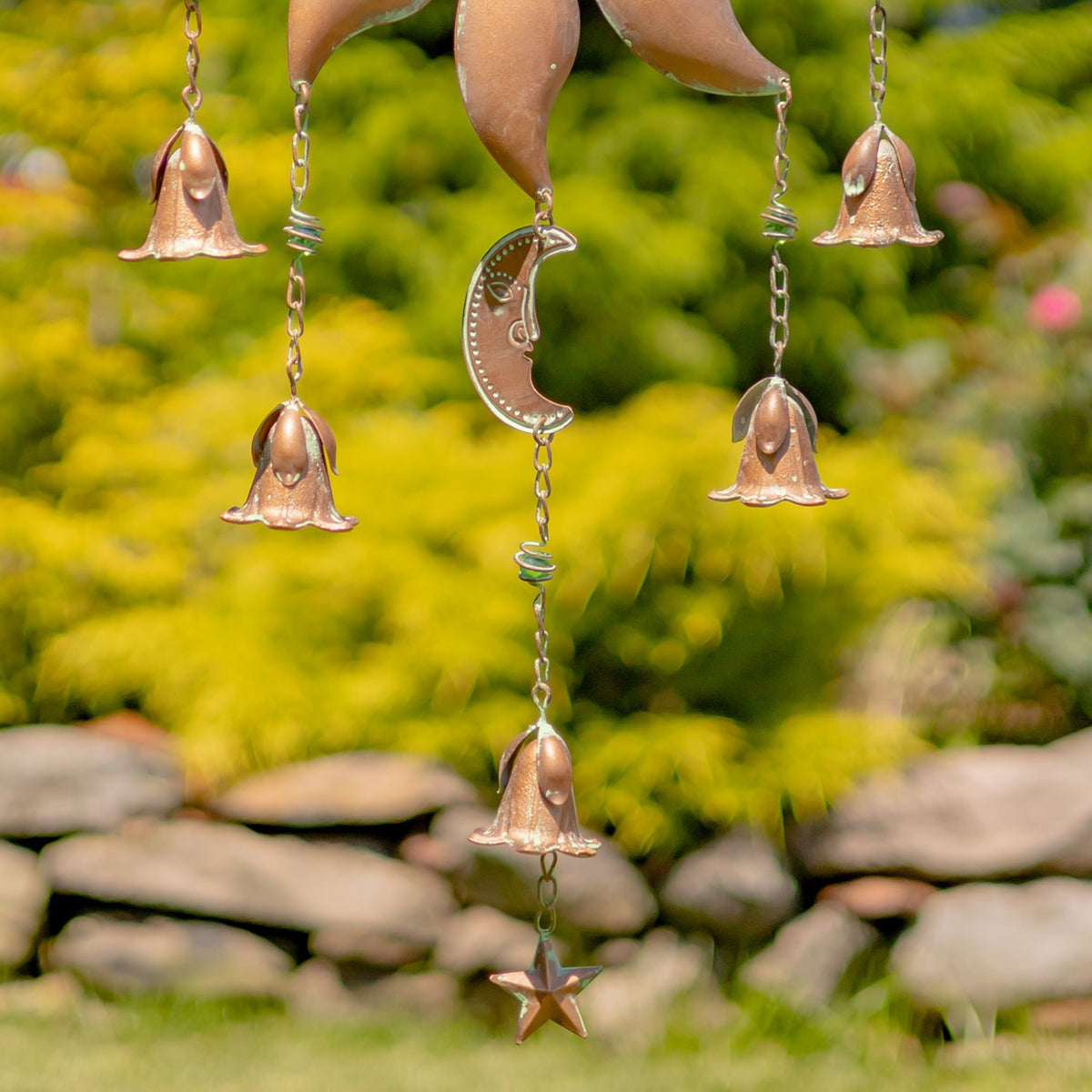 Close-up of the sun chime’s hanging bells, linked chains, crescent moon charm and star pendant.