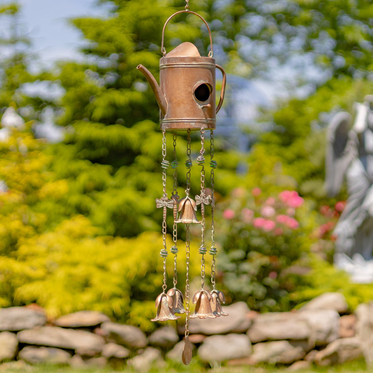Tall copper-colored teapot wind chime with a curved handle, bird opening, dangling chains, and several bells.