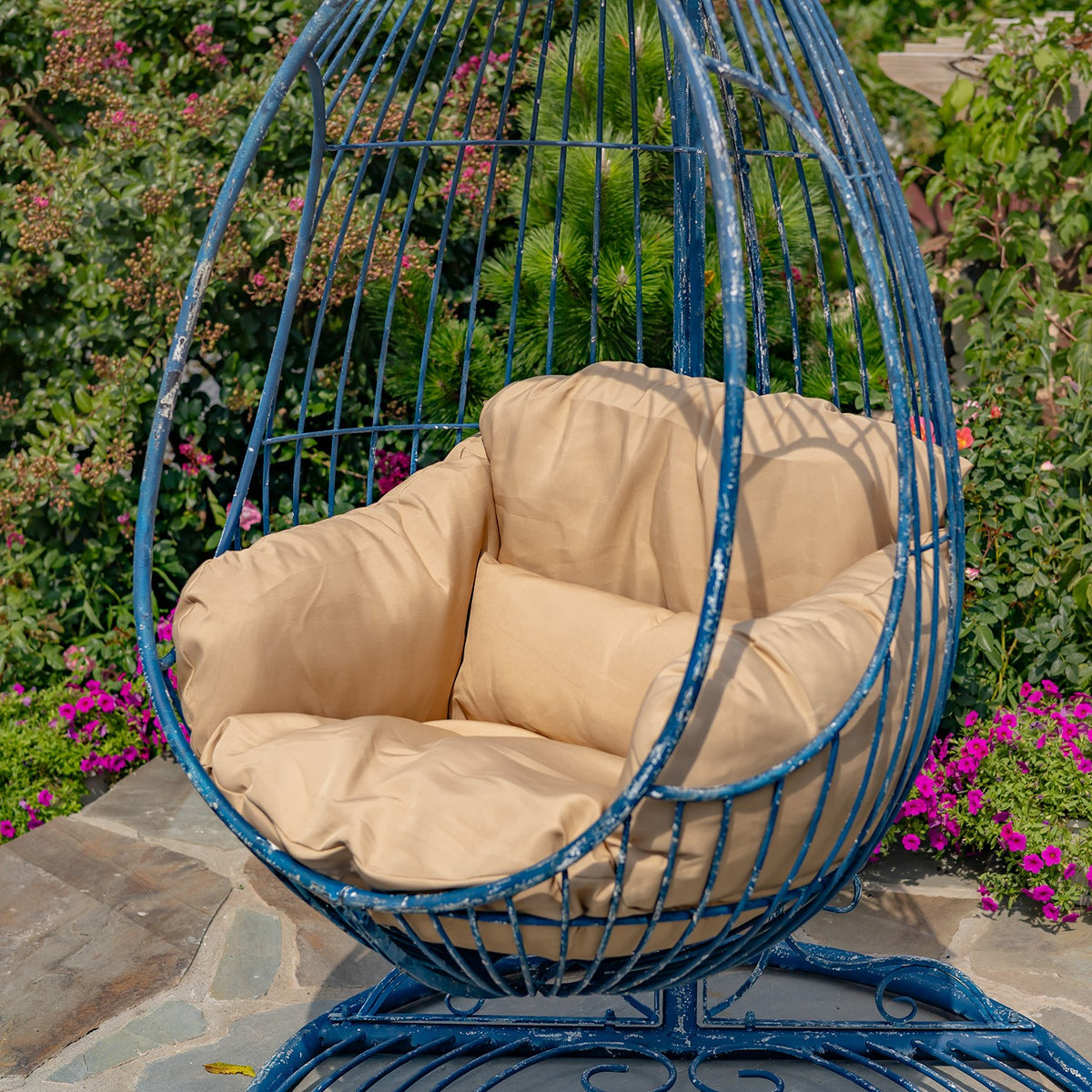 Angled close view of the blue egg chair, tan cushions, and curved metal stand.