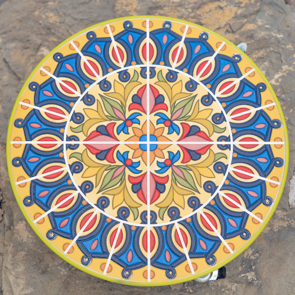 Overhead view of a round trolley top with an intricate blue, yellow, and coral floral mosaic.