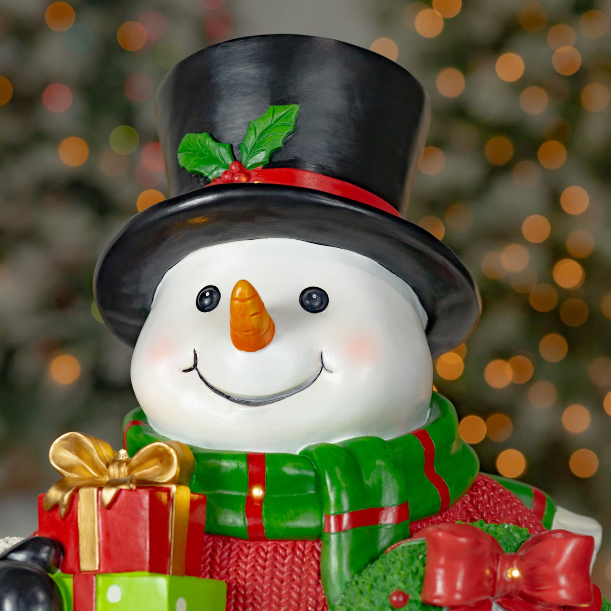 Close-up of the snowman's smiling face, holly-trimmed hat, scarf and the edge of its wreath.