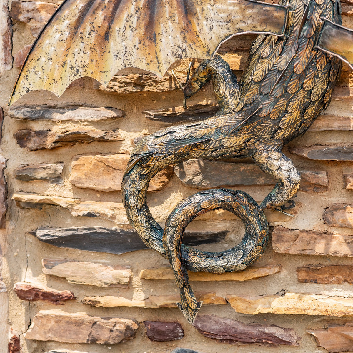 Close-up of the dragon’s curled tail and engraved scale pattern beneath one wing.