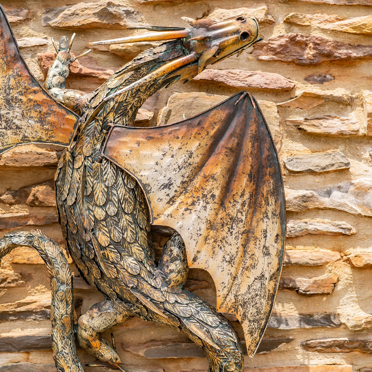 Angled view of the dragon sculpture showing its scaled body, raised head, and broad wing.