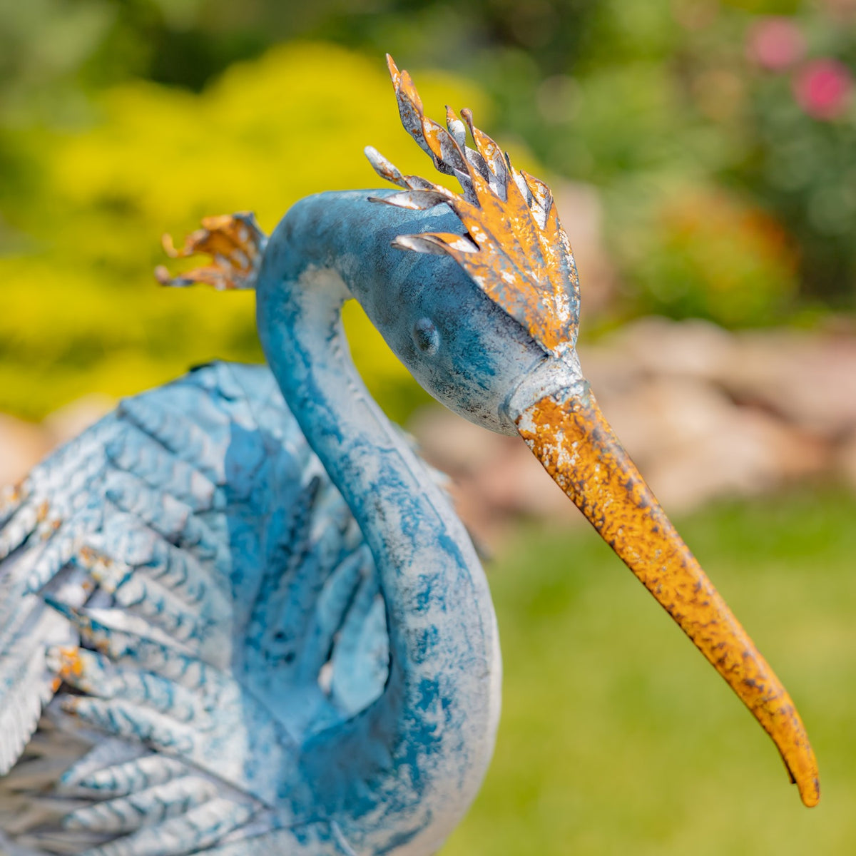 Close-up of a heron figurine's blue head, crest and long orange beak
