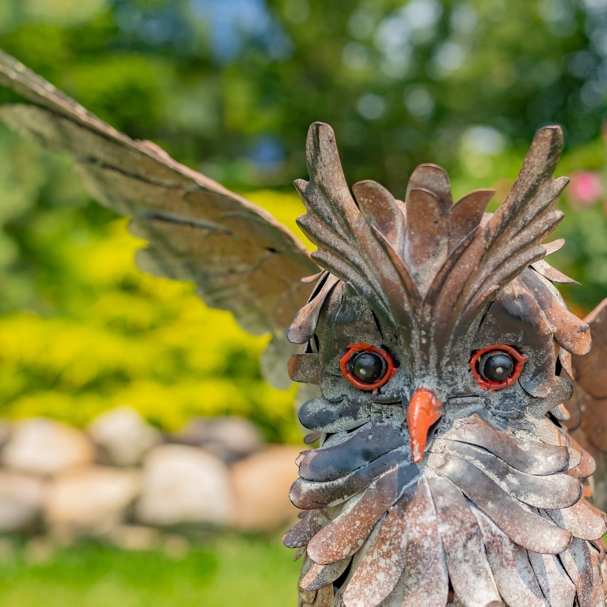Close-up of the owl’s layered metal feathers, orange beak, and round eyes.