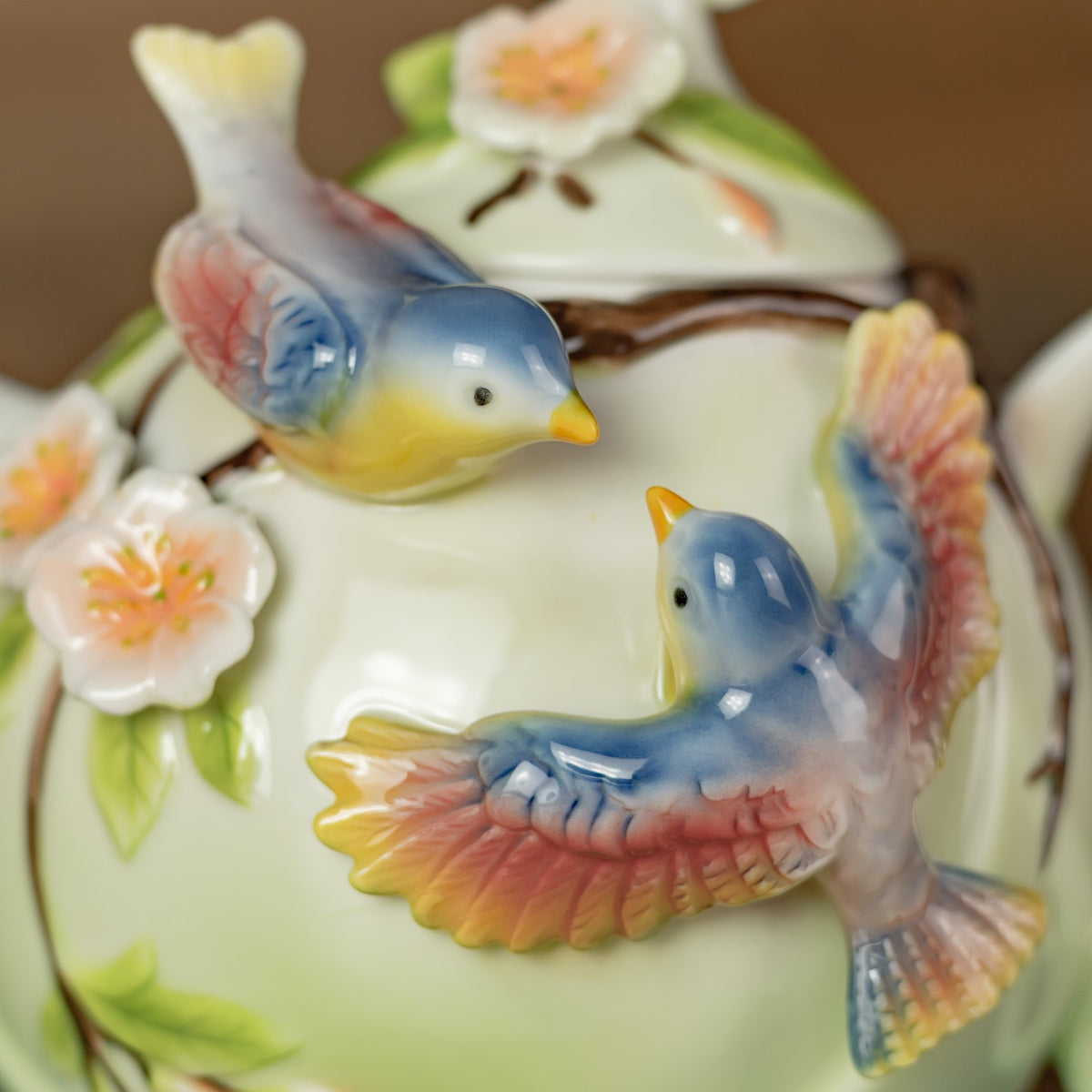 Close-up of two blue-and-pink birds and raised flowers decorating the teapot.