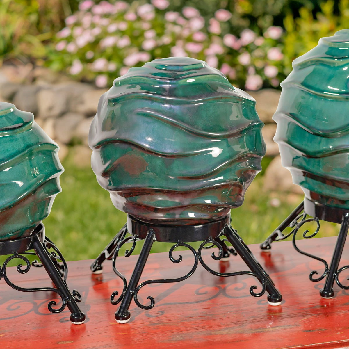 The middle-sized ridged teal globe and its curled metal stand are shown between two partially cropped globes.