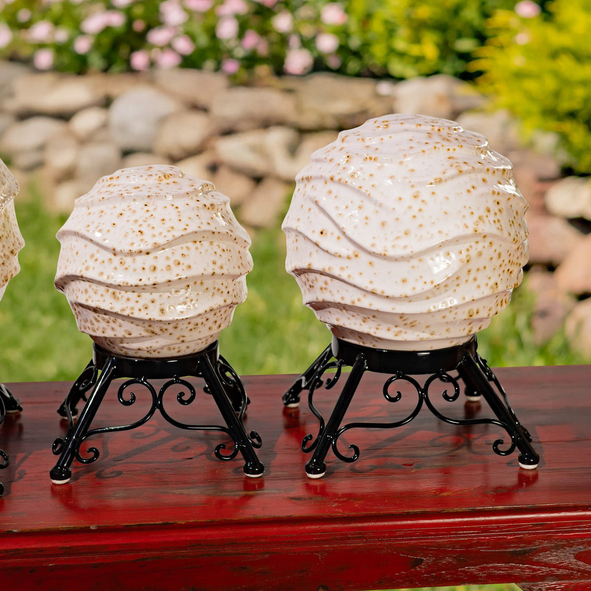 Two speckled globes on curled black stands, the larger one positioned on the right.