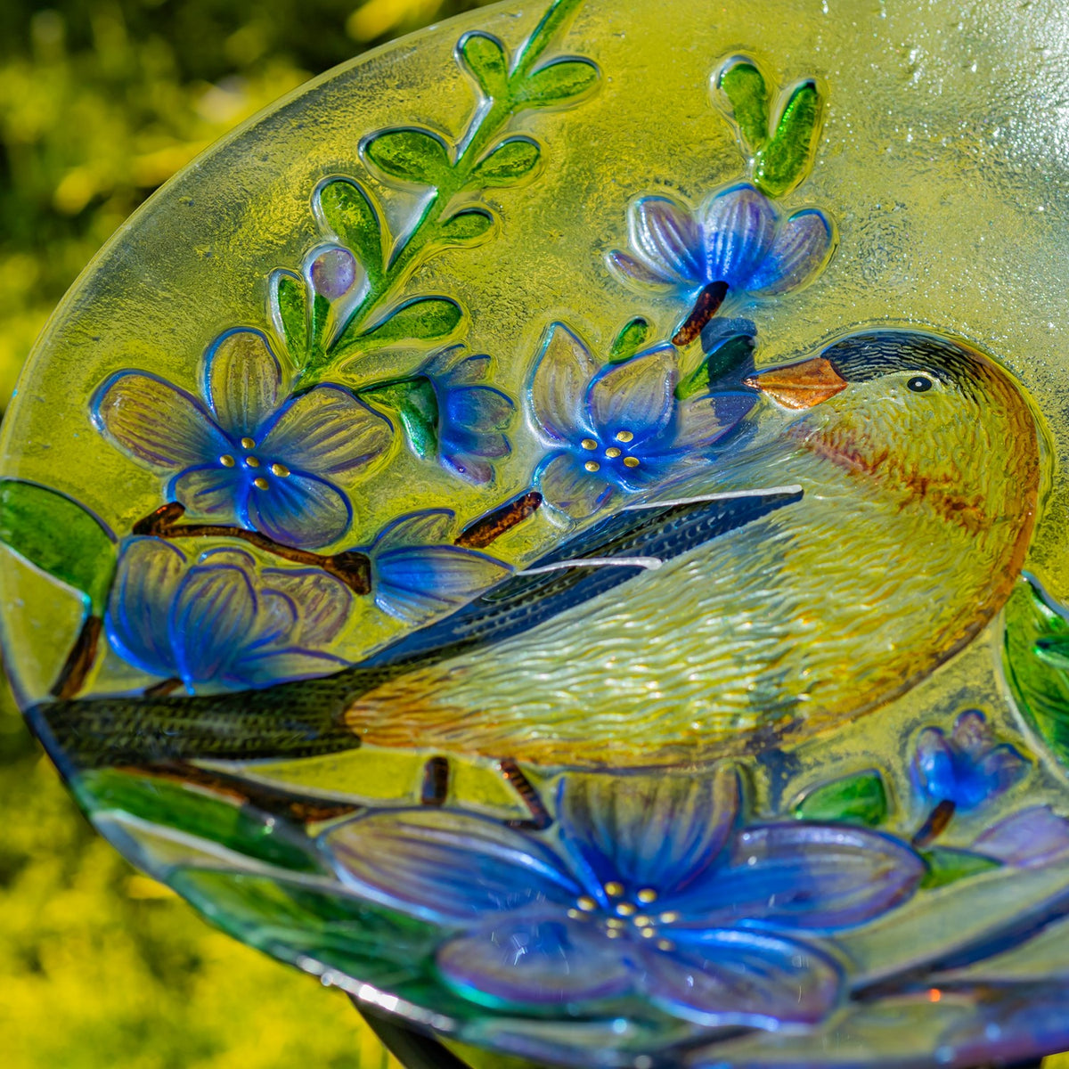 Close-up of the glass bowl’s goldfinch, textured feathers, and raised blue flowers and green leaves.