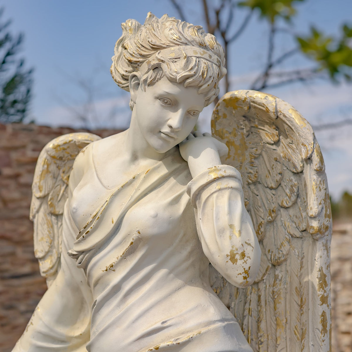 Close view of the angel’s face, curled hair, draped shoulder, and weathered wing.