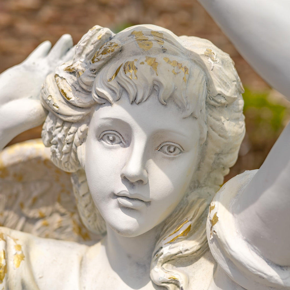 Close-up of the angel’s sculpted face, curled hair, and distressed gold-toned accents.