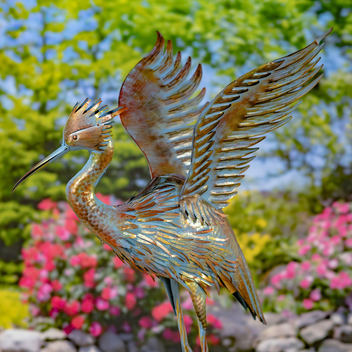 Close view of a metal heron sculpture with one wing lifted and its long beak pointed left.