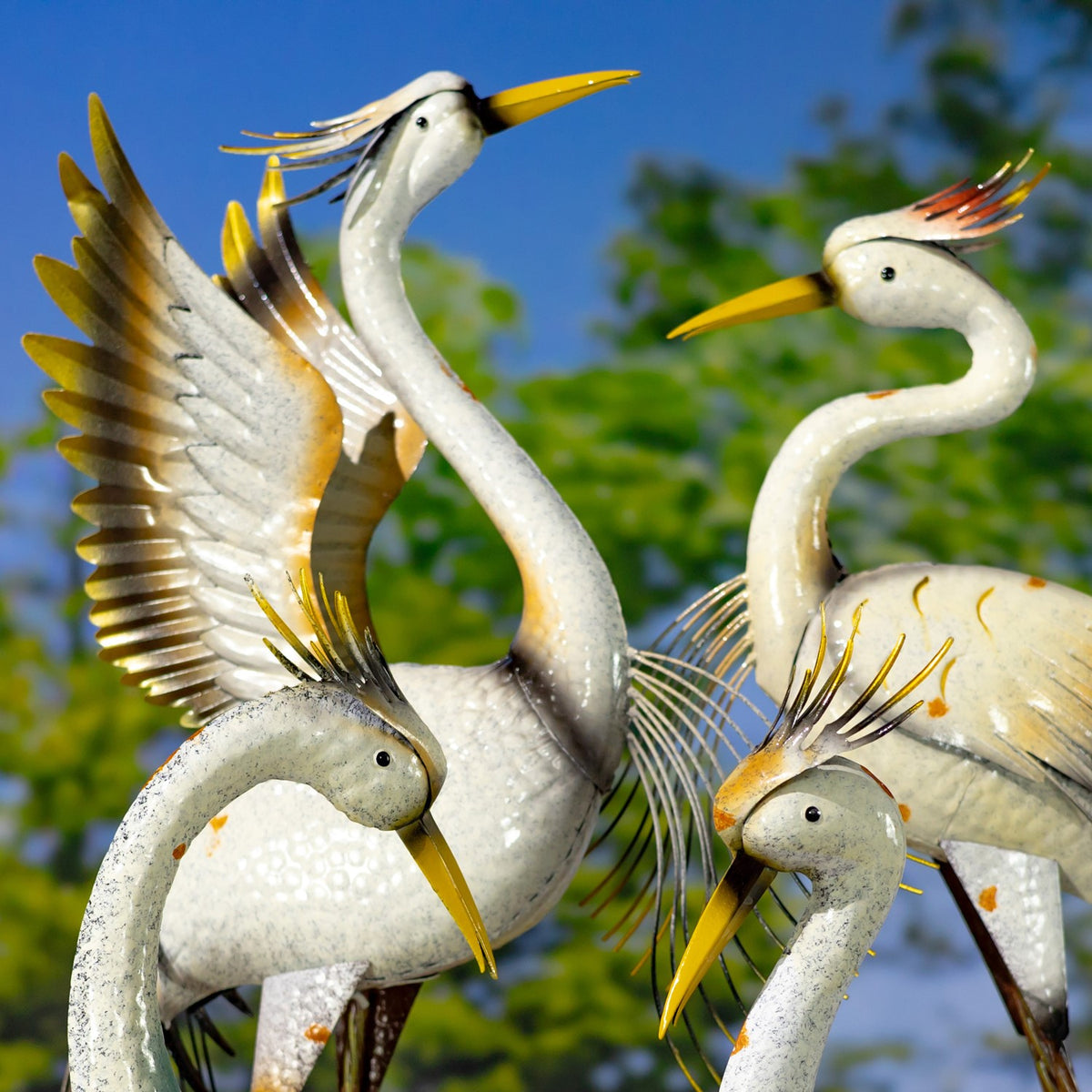 A closer view of the four heron figures shows curved necks, painted feathers, and long beaks.