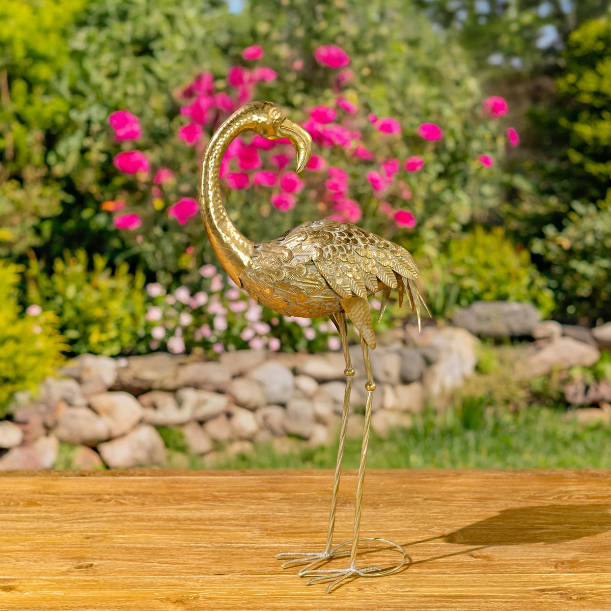 A gold flamingo figurine stands in profile with its curved neck, textured body, and long legs visible.