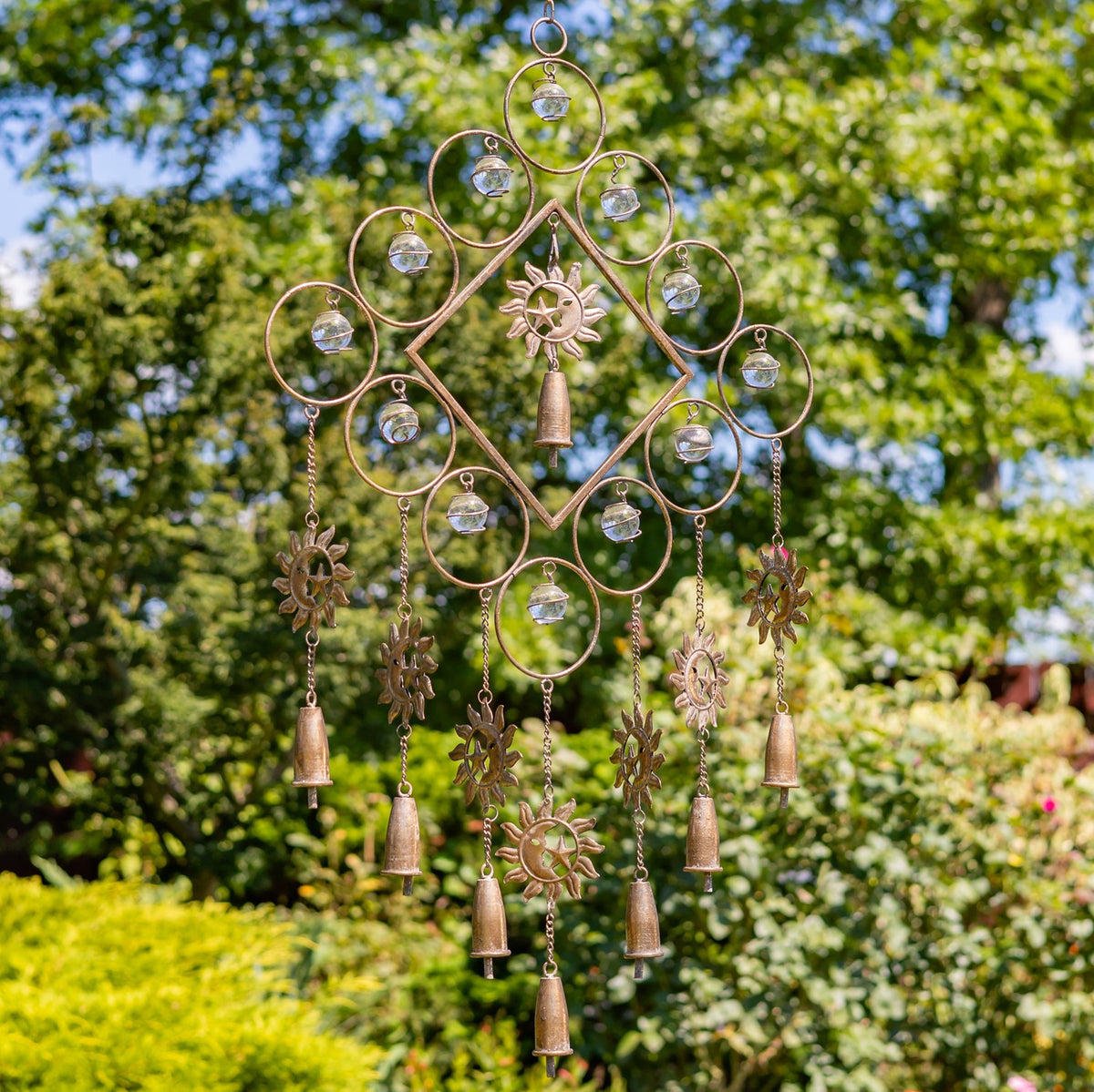 Metal wind chime with a diamond frame, round glass-like accents, sun details, and several hanging bells.