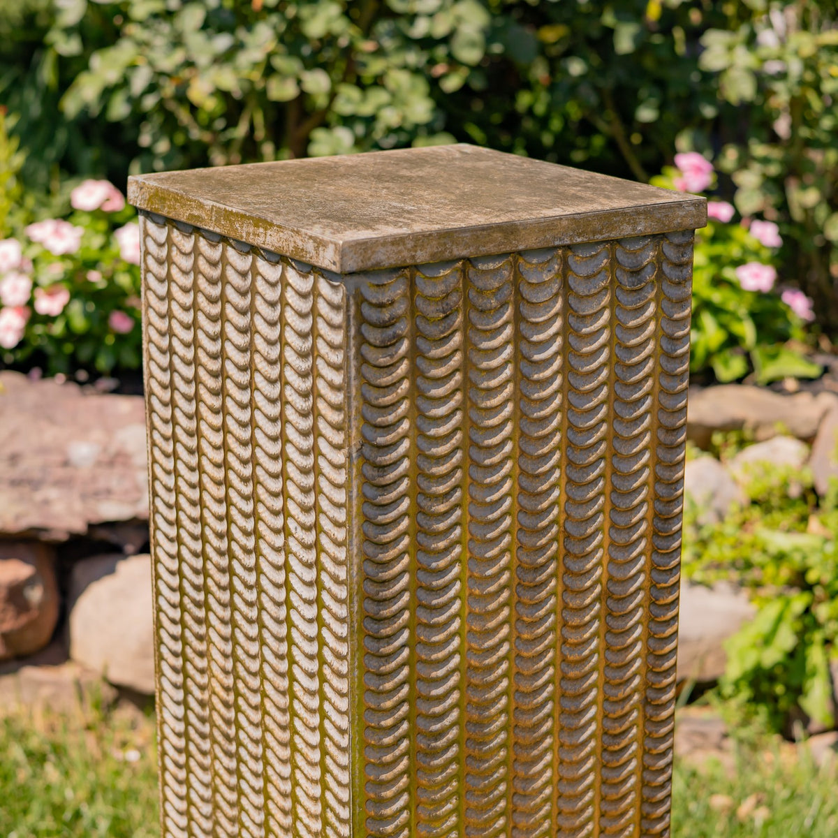 Close view of one pillar’s repeating raised scallop pattern and mottled square top.