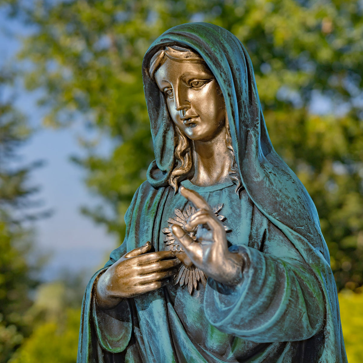 Close view of Mary's face, draped hood, raised hand, and the rays surrounding her heart.