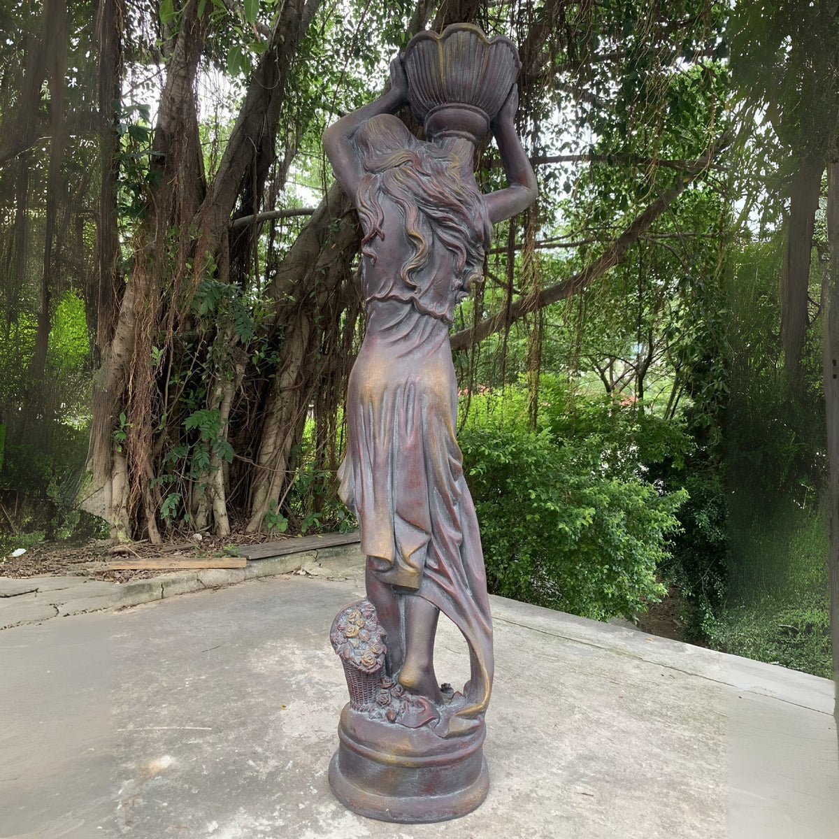 The statue is shown from behind, revealing the draped back of her dress and the sculpted base.