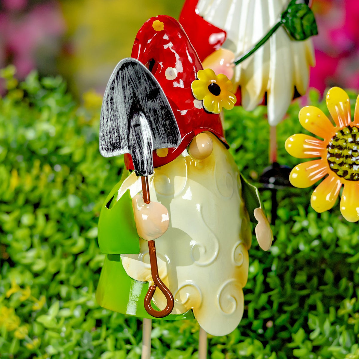 A gnome in a red spotted hat holds a small gray shovel beside a raised swirl on its cream coat.