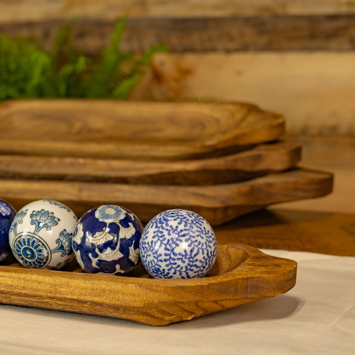 Blue-and-white patterned balls sit in a wooden tray, with three more trays stacked in the background.
