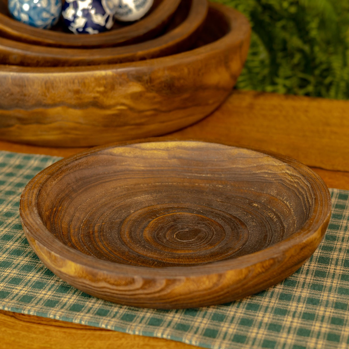 Close-up of an empty round wooden tray showing its raised rim and swirling grain.