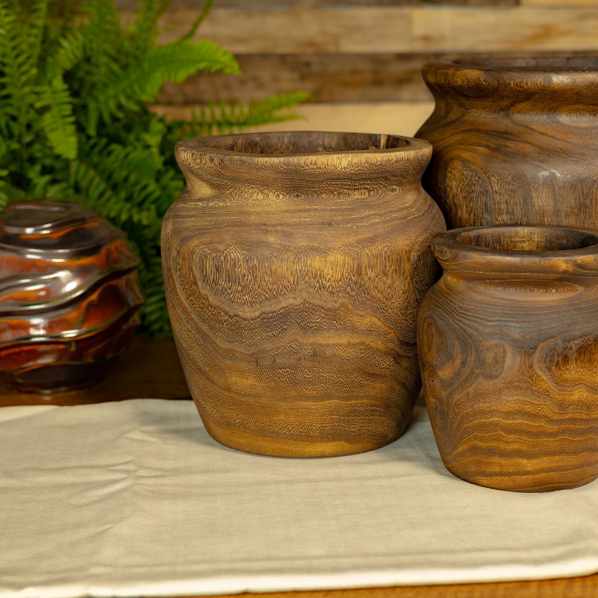 Three brown planters of varying sizes grouped together on a light cloth.