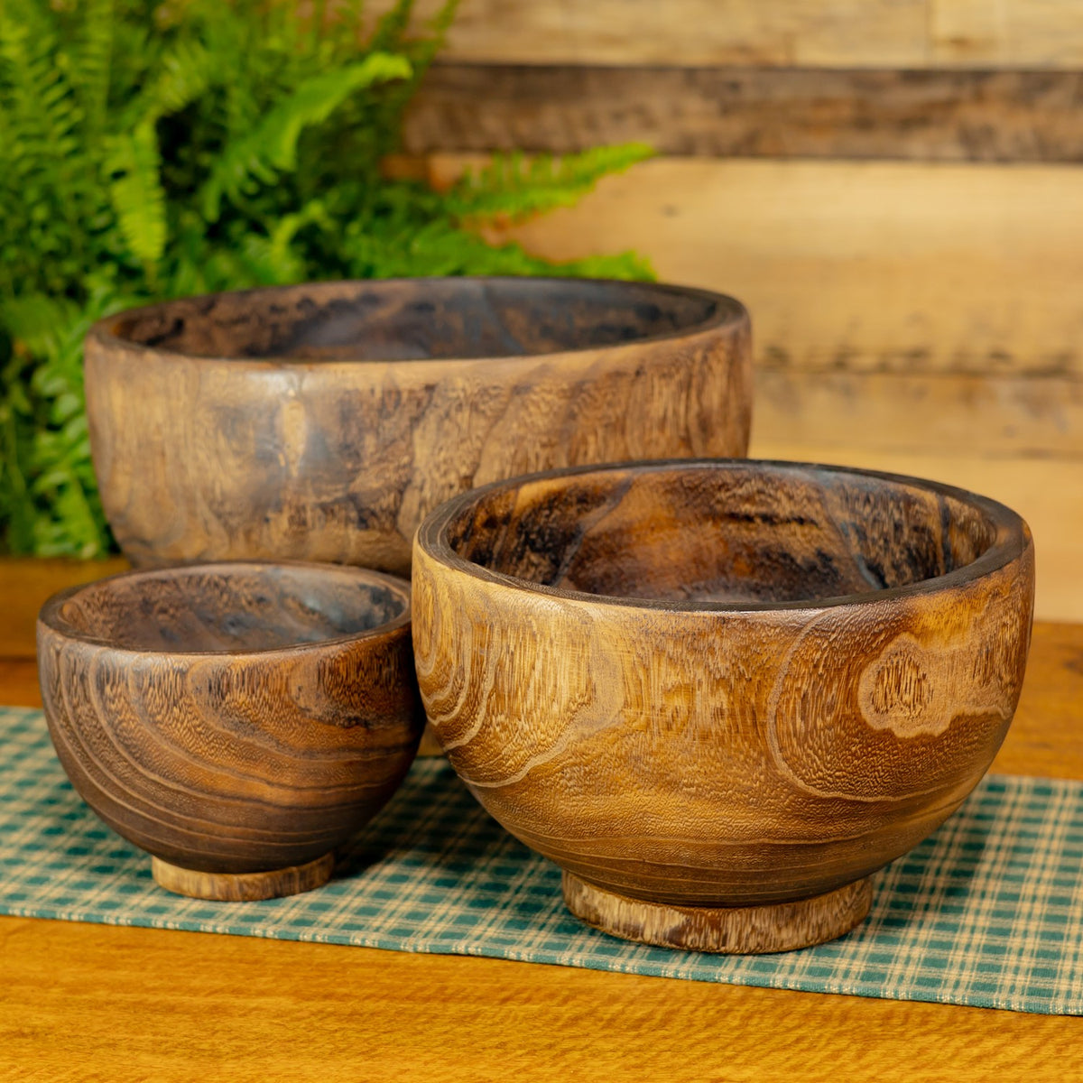Three empty round wooden bowls in graduated sizes show their carved grain and dark interiors.