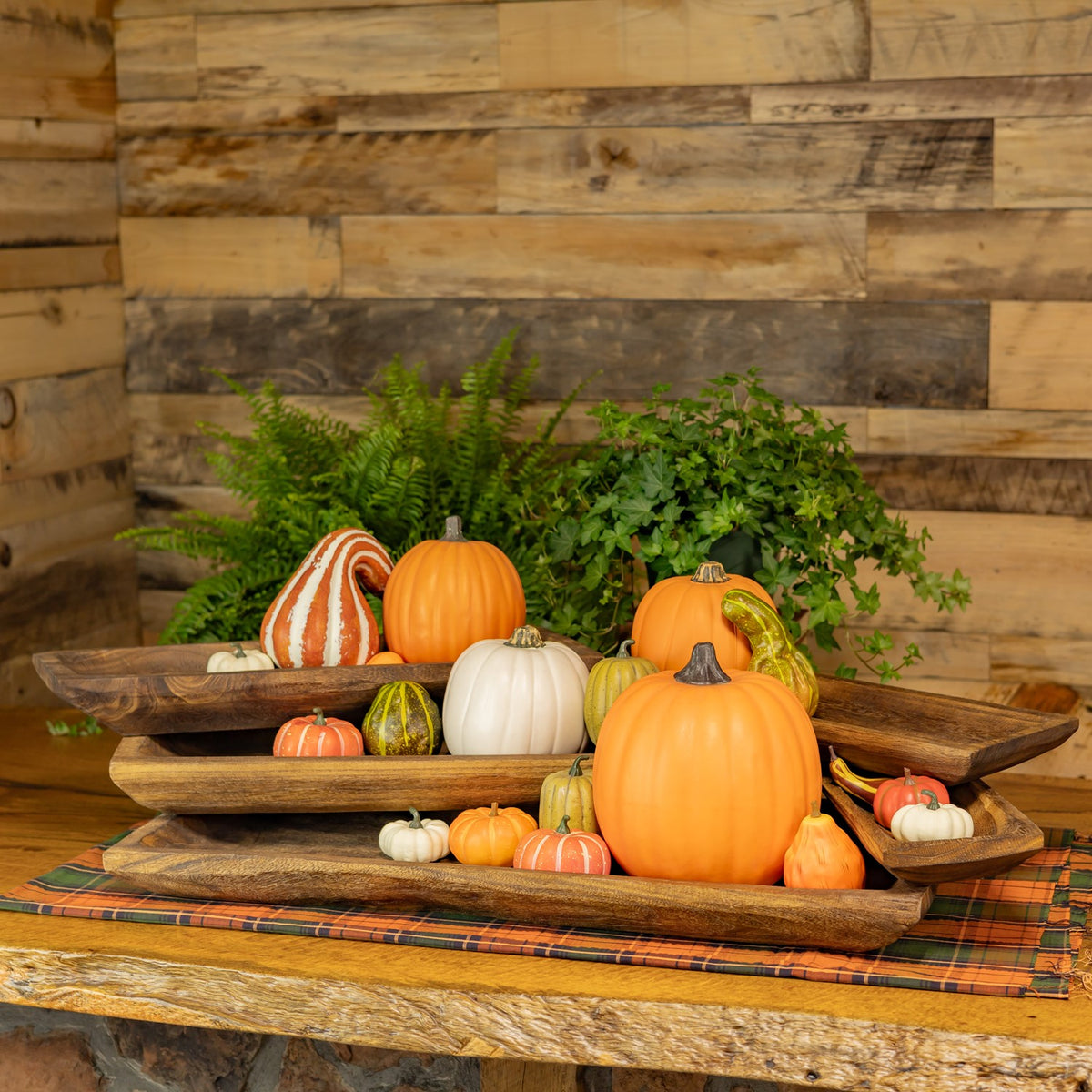 Nested wooden trays arranged with assorted orange, white, and striped pumpkins and gourds.