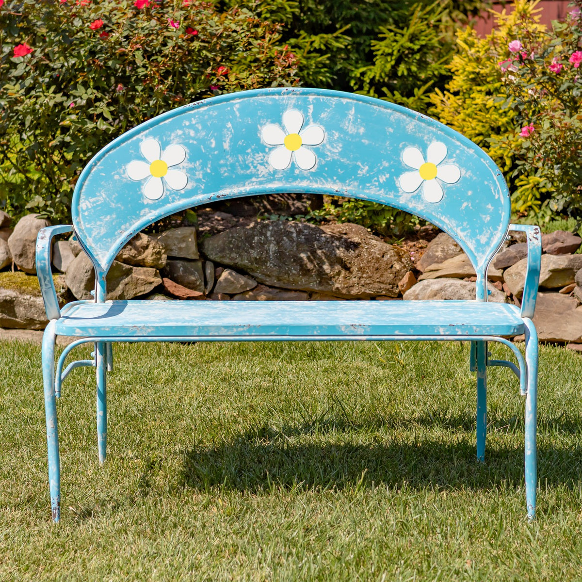 Front view of a blue garden bench showing three white flowers across its arched backrest.
