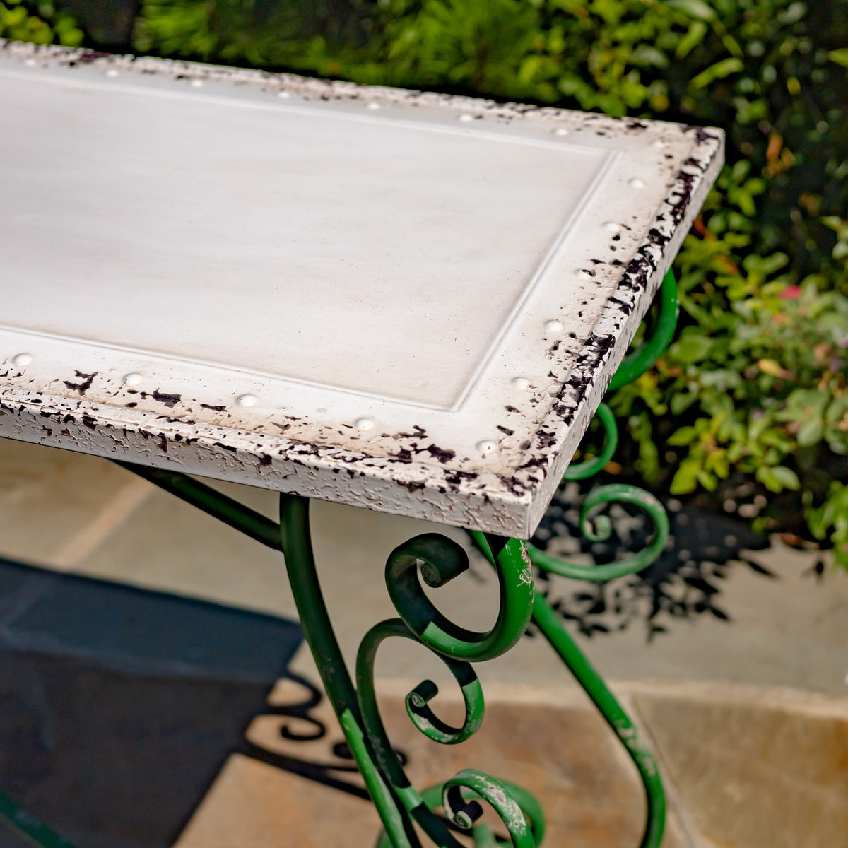 Close-up of the white tabletop's raised inset center and distressed dark marks along its edge.