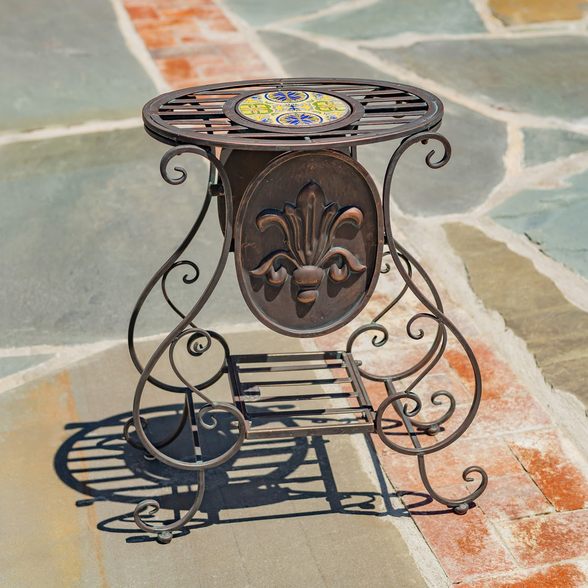An ornate plant stand viewed from the front, showing its scrollwork frame and patterned tile top.